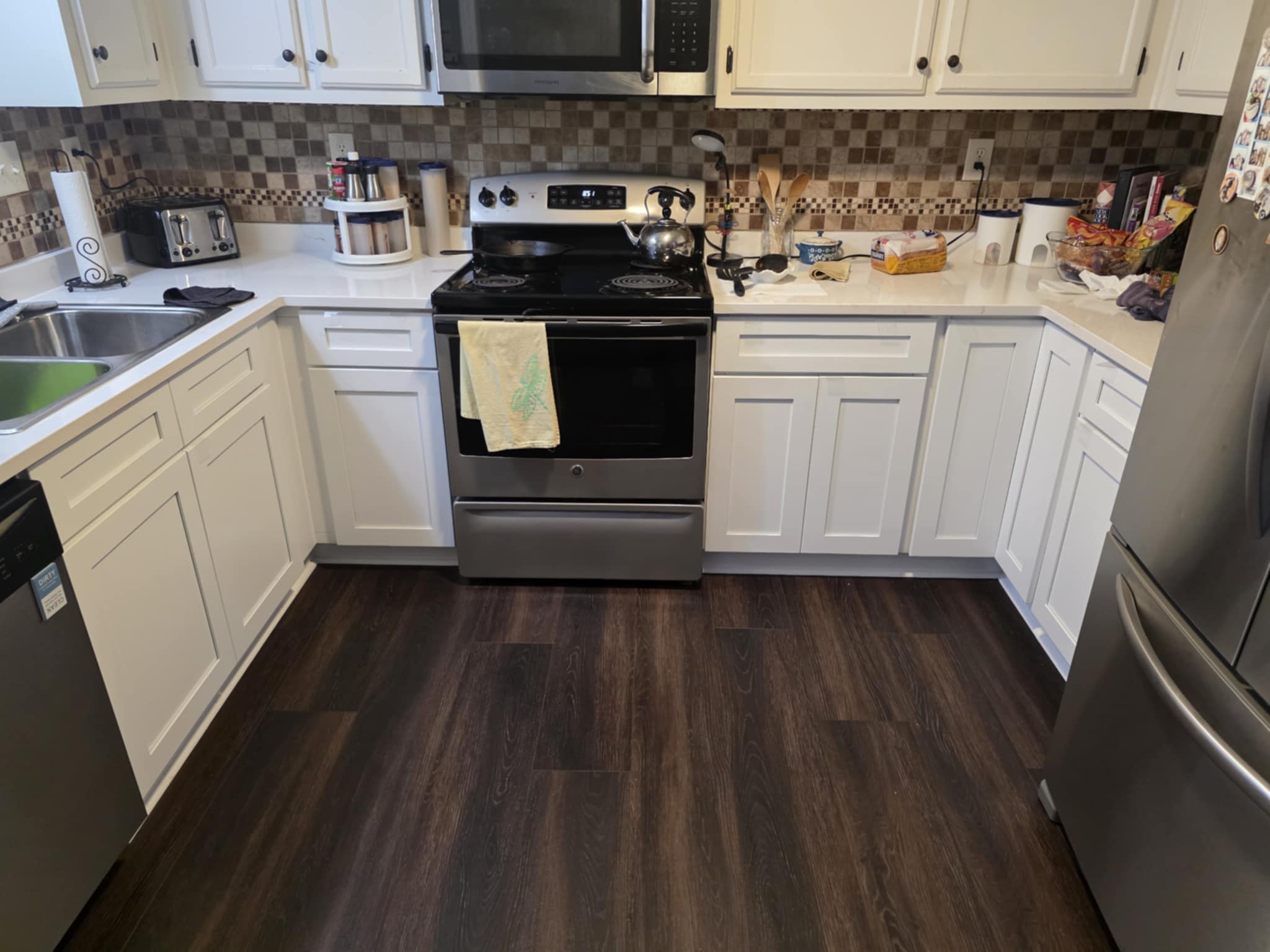 Completed kitchen remodel with white cabinets and dark flooring